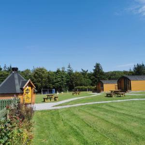 a park with benches and picnic tables and buildings at Greencraig Pods in Buckie