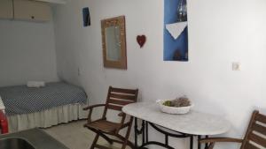 アナフィにあるTraditional Renovated House in the Centre of Anafiのテーブル、椅子、ベッドが備わる客室です。