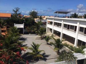 un edificio blanco con palmeras delante en Lofts Dois Corações, en Cabo Frío