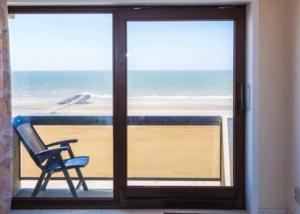 a view of the beach from a window with a chair at De Winner in Middelkerke