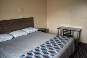 a bedroom with a large bed and a desk at Inn of Lenoir Motor Lodge in Lenoir City