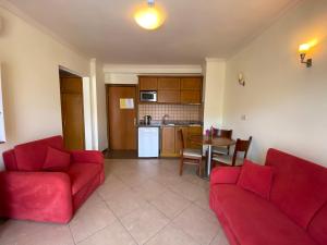 a living room with two red couches and a kitchen at Club Karakas Apart Otel in Marmaris