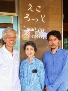 a woman and two men standing in front of a sign at えころっじKitsuki in Kitsuki