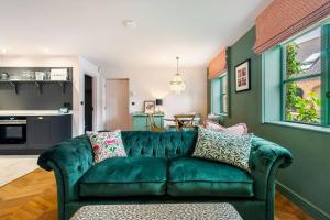 a green couch in a living room with a kitchen at The Cottage - Luxury Romantic Retreat in Idyllic Rural Location in Clipston