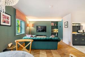 a living room with a green couch and a tv at The Cottage - Luxury Romantic Retreat in Idyllic Rural Location in Clipston