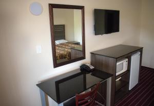 Habitación de hotel con TV y espejo. en Kings Inn, en Lenoir City