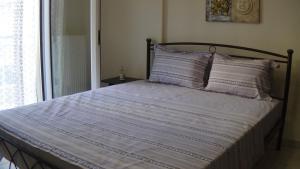 Una cama con una manta azul y blanca y una ventana en Anastasia's & Despoina's Apartment, en Serres