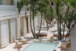 a pool with chairs and palm trees next to a building at Cara Hotel in Los Angeles