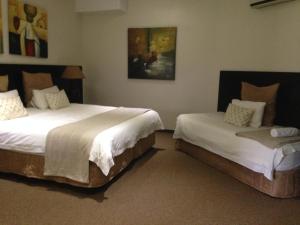 een slaapkamer met 2 bedden en een schilderij aan de muur bij The Waterfront Country Lodge in Vaalview