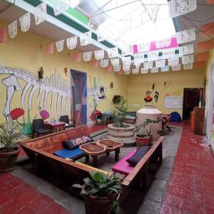 Habitación con bancos, mesas y una pared con tablas de surf. en Iguana Hostel Oaxaca, en Oaxaca City