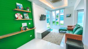 a green accent wall in a living room with a couch at Khung Wimarn Beach home by 3Angels in Chanthaburi