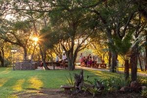 um grupo de pessoas sentadas em mesas de piquenique em um parque em Summerset Place Country House em Bela-Bela