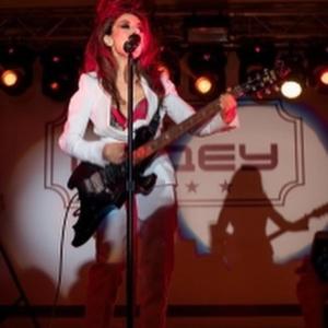 une femme aux cheveux rouges jouant de la guitare sur une scène dans l'établissement Medeu, à Kostanay