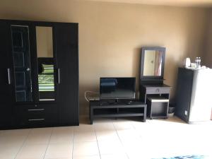 a living room with a door and a television and a tv stand at The State Apartment in Bangkok