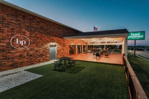 un edificio de ladrillo con un patio con mesas y sillas en Hotel Pommier Indianola, en Indianola