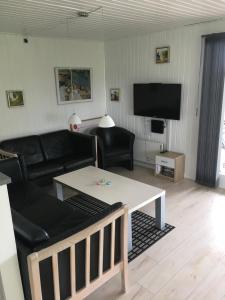 sala de estar con sofá negro y mesa en cottage close to Hasmark beach 150m, en Otterup