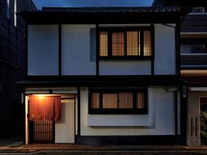 una casa blanca con una puerta con una cortina roja en Tsumugi Nishinotoinhanayacho, en Kioto