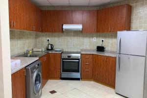 a kitchen with a white refrigerator and a dishwasher at Cozy 2BHK Near to DMCC Metro Station -505 in Dubai