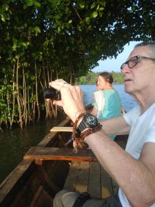 a man taking a picture of a boat on the water at Royal Munroe Palace Home Stay in Munroe Island