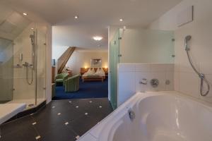 a bath room with a tub and a sink at Parkhotel Gunten – Beach & Spa in Gunten