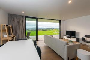 a living room with a couch and a tv and a room with a view at Karapiro BlackBox in Karapiro