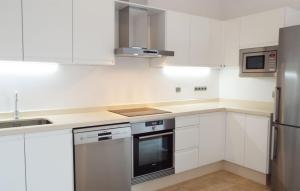 a kitchen with white cabinets and a stainless steel refrigerator at Casa Can Relax in Es Pujols