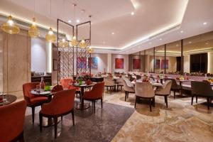 a restaurant with tables and chairs in a room at The Pride Hotel, Nagpur in Nagpur