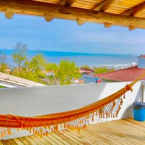 un balcón con hamaca y vistas al océano en Bella Vista Kitnets en Farol de Santa Marta