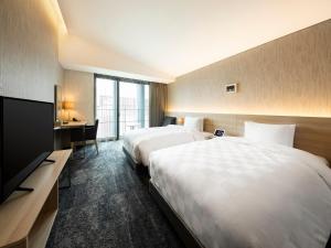 a hotel room with two beds and a flat screen tv at Hotel Royal Classic Osaka in Osaka