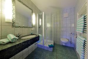 a bathroom with a sink and a toilet and a mirror at Hotel Zum Adler in Nidderau