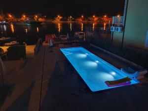 una piscina di fronte all'acqua di notte di Apartments Pralas a Mokošica