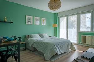 a bedroom with blue walls and a bed and a table at Le Colibri - Stationnement gratuit - Balcon - Jusqu'à 4 personnes in Metz