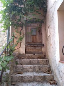 a wooden door on the side of a building with stairs at Au Relais Fleuri in Gilette