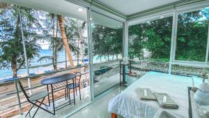 a bedroom with a bed and a view of the beach at Khung Wimarn Beach home by 3Angels in Chanthaburi