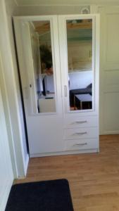 ファルケンベリにあるGäststugaの鏡付きの白いキャビネットが備わる客室です。