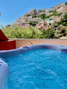 una piscina con sedia rossa e una montagna di Hotel Savoia a Positano