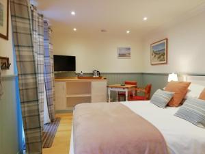 1 dormitorio con cama, escritorio y cocina en Sea Breeze en Freshwater