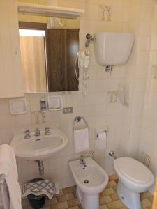 a white bathroom with a sink and a toilet at Hotel Luana in Chianciano Terme