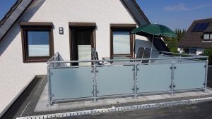 a balcony of a house with a green umbrella at Appartementhaus Diana in Grömitz