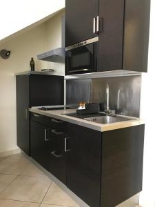 a kitchen with black cabinets and a sink at Lo Squero Rooms and Apartments in Fano
