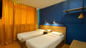 Zwei Betten in einem Zimmer mit blauen und orangen Wänden in der Unterkunft Uptown Hotel in Semporna