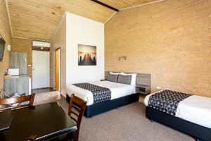 Cette chambre d'hôtel dispose de 2 lits et d'un mur en briques. dans l'établissement Lookout Mountain Retreat, à Dorrigo