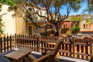 a wooden bench in front of a fence with a tree at Petani Bay Hotel - Adults Only in Vóvikes