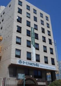 a tall building with a sign in front of it at Terminal Hotel Matsuyama in Matsuyama