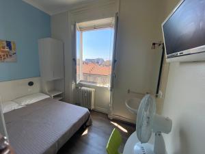 una piccola camera con un letto e una grande finestra di Hotel Kennedy a Milano