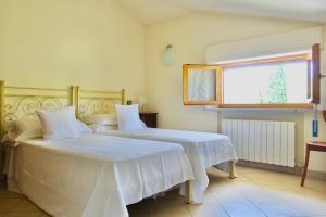 um quarto com 2 camas com lençóis brancos e uma janela em Casa GINESTRA a Bagno Vignoni em Bagno Vignoni