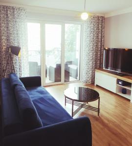 a living room with a blue couch and a tv at Apartament Niebieski in Świnoujście