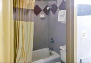 a bathroom with a shower with a yellow shower curtain at USA Inn in Alcoa