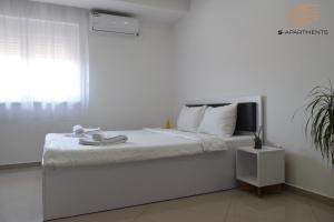 a white bedroom with a bed with a window at S-Apartmani Cocetova in Jagodina