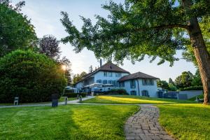 ein weißes Haus mit einem Baum und einem Gehweg in der Unterkunft Hostellerie Le Petit Manoir in Morges